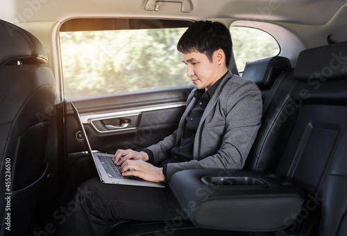 business man using laptop computer while sitting in the back seat of car © geargodz