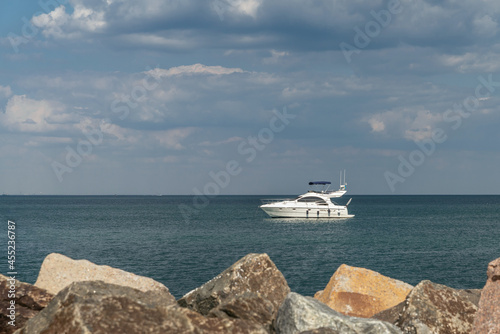 A small boat yacht in the sea near the shore. Beautiful clody sky on background. photo