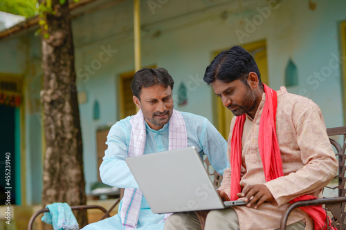 Technology concept : Indian farmers using laptop at home.