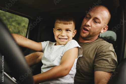 Father teaches little son to drive on road trip
