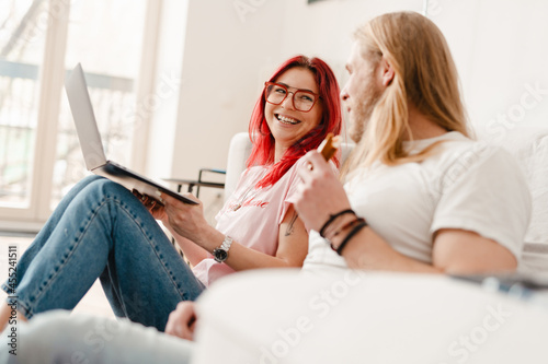 White man and woman using laptop together while sitting on floor