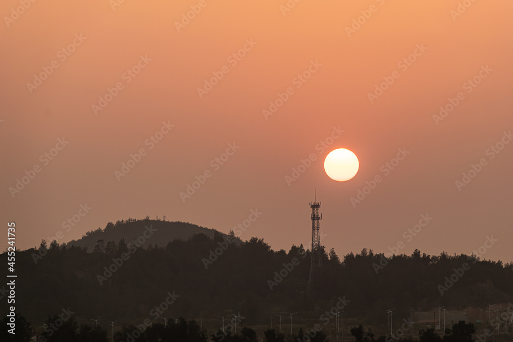 The setting sun is above the telecommunication signal tower on the mountain The setting sun is above the telecommunication signal tower on the mountain