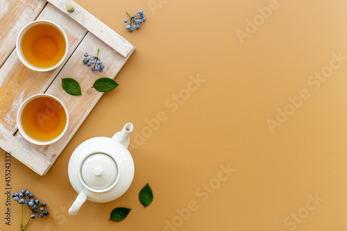 Ceramic white teapot and black tea in two cups, top view