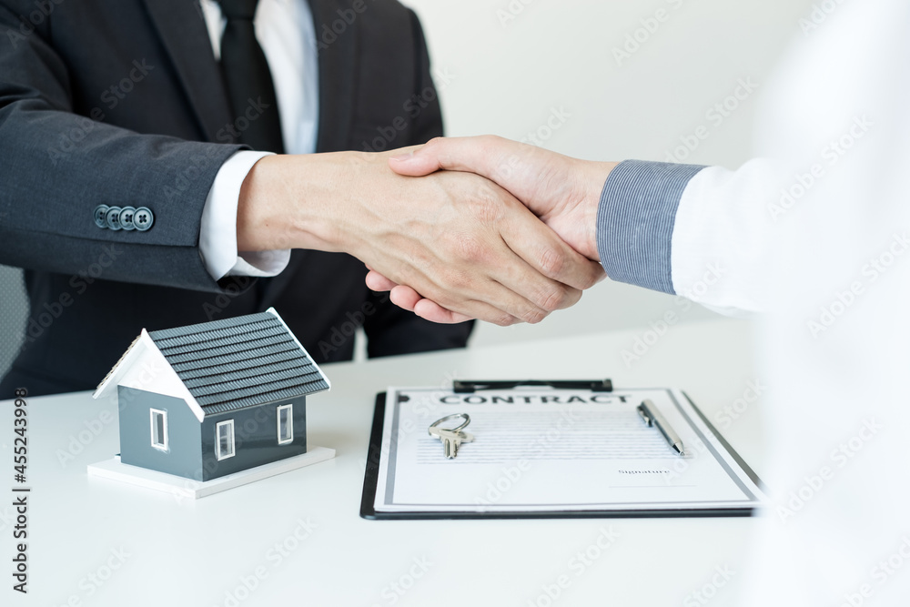 Businessmen and brokers' real estate agents shake hands after completing negotiations to buy houses insurance and sign contracts. Home insurance concept Businessmen and brokers' real estate agents shake hands after completing negotiations to buy houses insurance and sign contracts. Home insurance concept