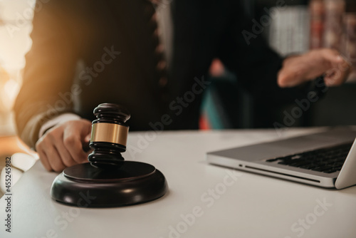 Close up view of auction hammer on the desk in lawyer office and lawyer writing document as courtroom.