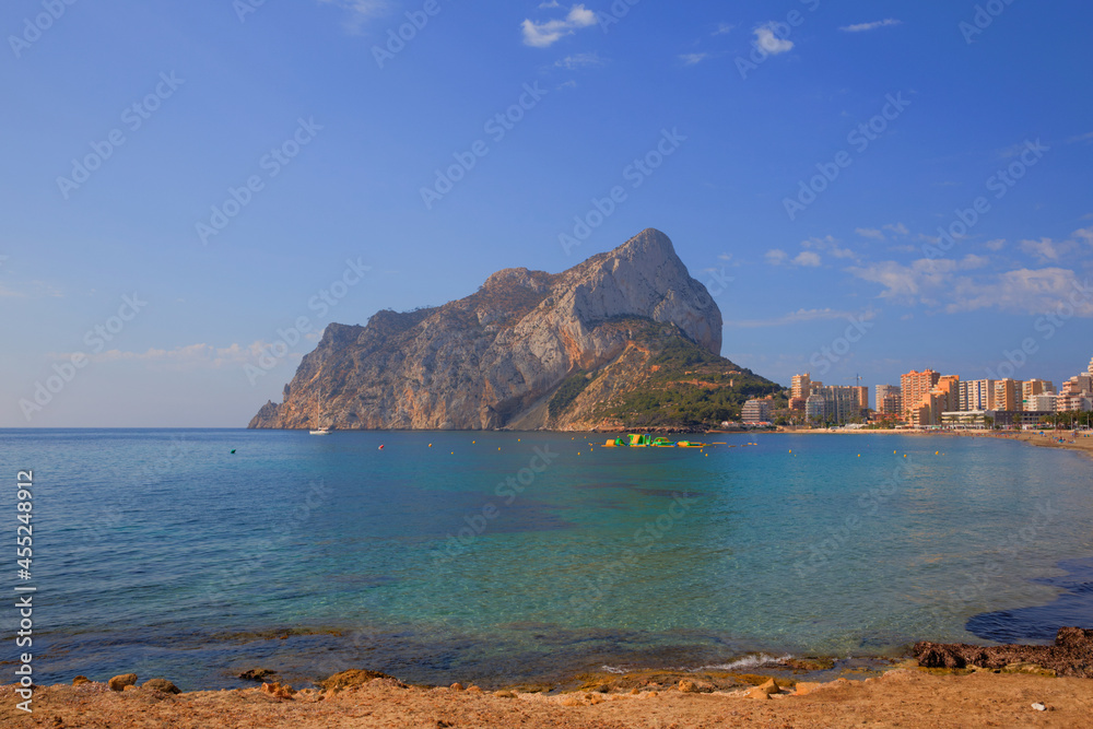 Calp Spain rock from Levante La Fossa beach colourful blue sea and sky
