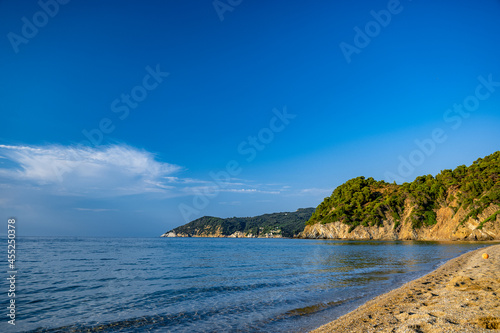 Remote beach with azure clear water and green hills