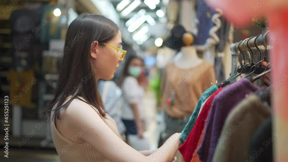 4K Asian woman shopping and buying fashion clothes at street market. Confidence female enjoy outdoor lifestyle activity choosing clothing hanging on clothes rack at clothing shop in shopping mall. 4K Asian woman shopping and buying fashion clothes at street market. Confidence female enjoy outdoor lifestyle activity choosing clothing hanging on clothes rack at clothing shop in shopping mall.
