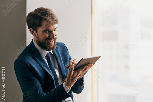Cheerful business man near the window with a tablet in his hands communication