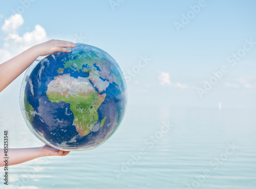 Inflatable ball in the hands of a child on the background of the sea