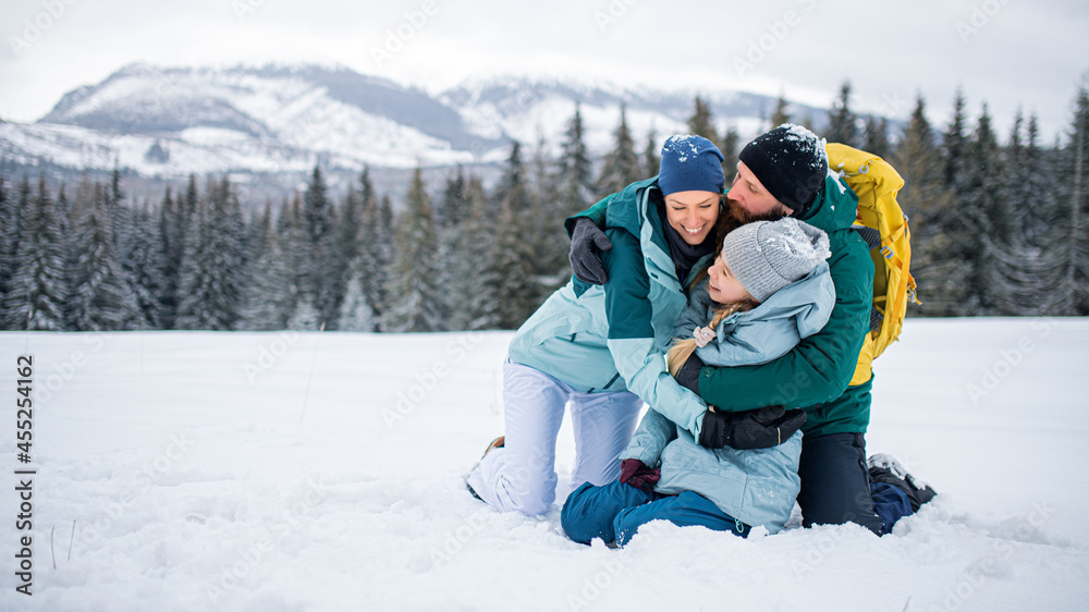 Family with small daughter hugging outdoors in winter nature, Tatra mountains Slovakia.
