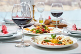 A served restaurant table with glasses of red wine and appetizer awaits guests. Close-up, selective focus