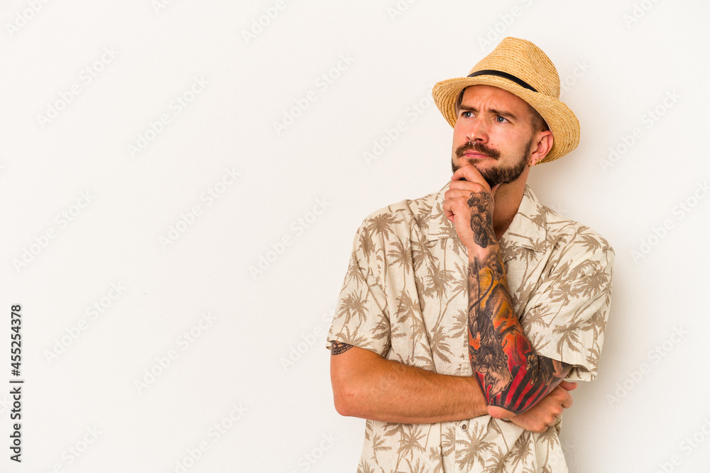 Young caucasian man with tattoos wearing summer clothes isolated on white background looking sideways with doubtful and skeptical expression. Young caucasian man with tattoos wearing summer clothes isolated on white background looking sideways with doubtful and skeptical expression.