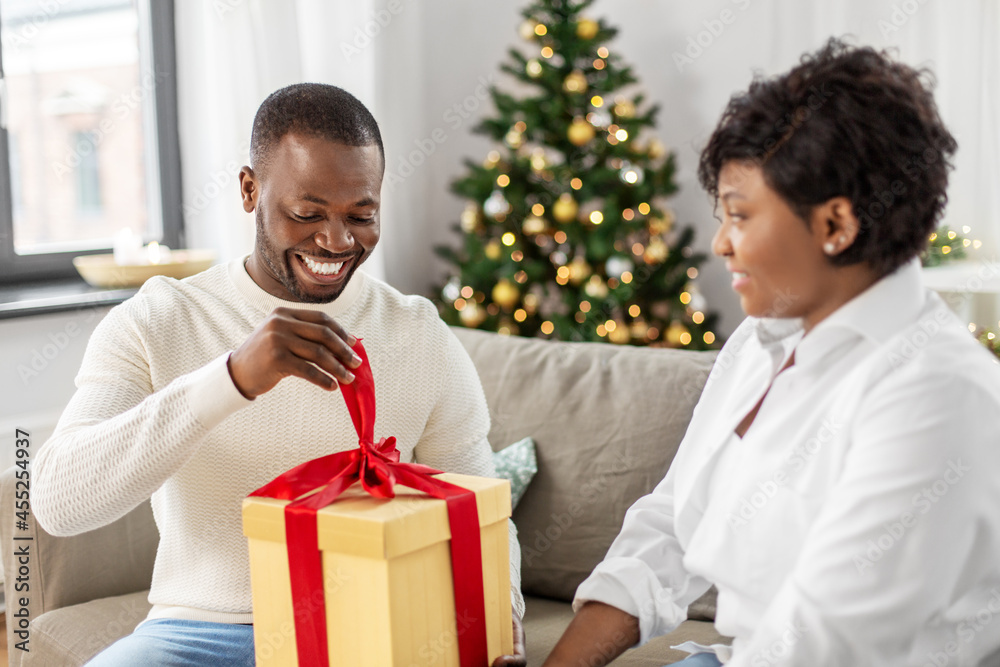 holidays, celebration and people concept - happy african american couple with christmas gift at home holidays, celebration and people concept - happy african american couple with christmas gift at home