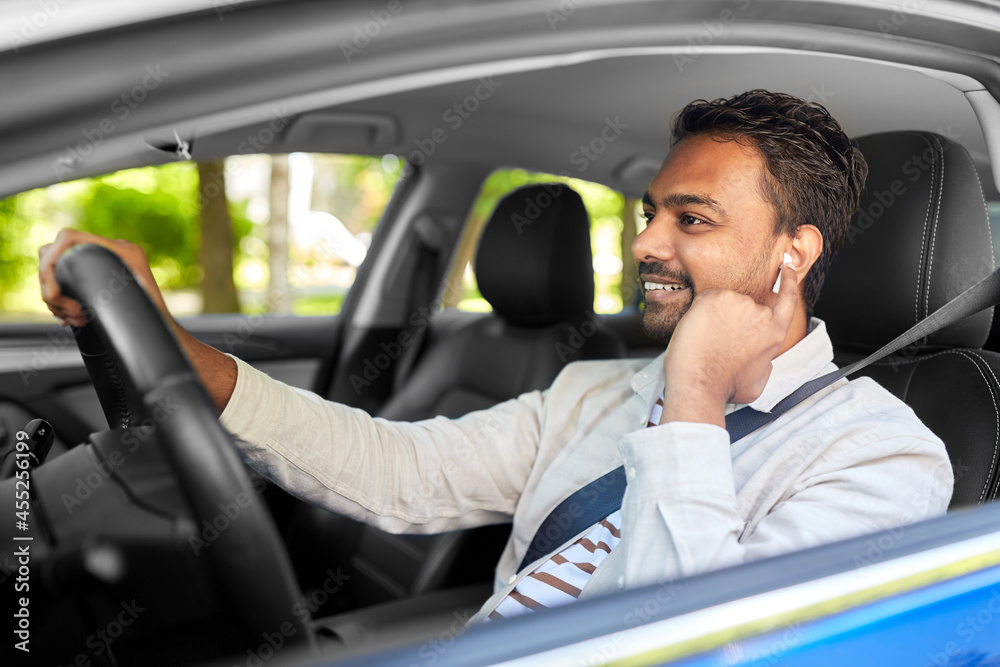 transport, people and technology concept - smiling indian man or driver with wireless earphones or hands free device driving car transport, people and technology concept - smiling indian man or driver with wireless earphones or hands free device driving car