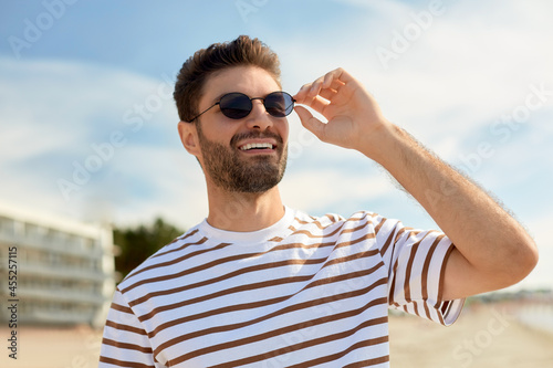 Slika na platnu summer holidays and people concept - portrait of young man in sunglasses on beac