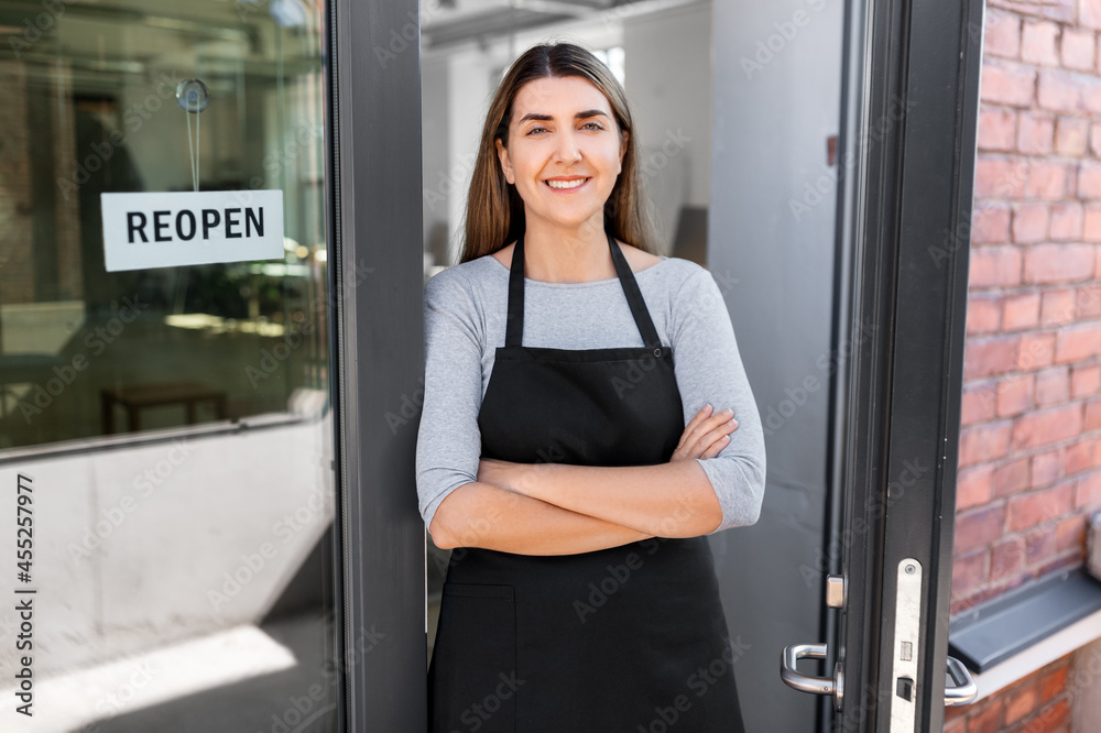 small business, reopening and service concept - happy smiling woman with reopen banner on window or door glass small business, reopening and service concept - happy smiling woman with reopen banner on window or door glass