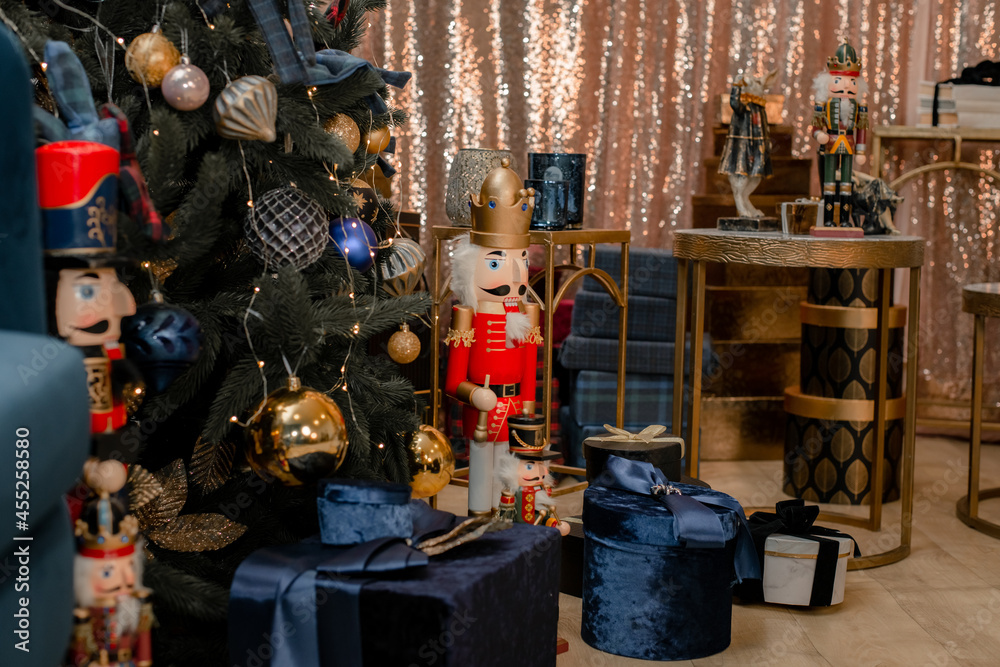 Christmas decoration Nutcracker. Tin soldiers on guard looks at gifts under the tree. Classic soldier figurine of nutcracker drummer in shape in front the background of a decorated New Year's blue 