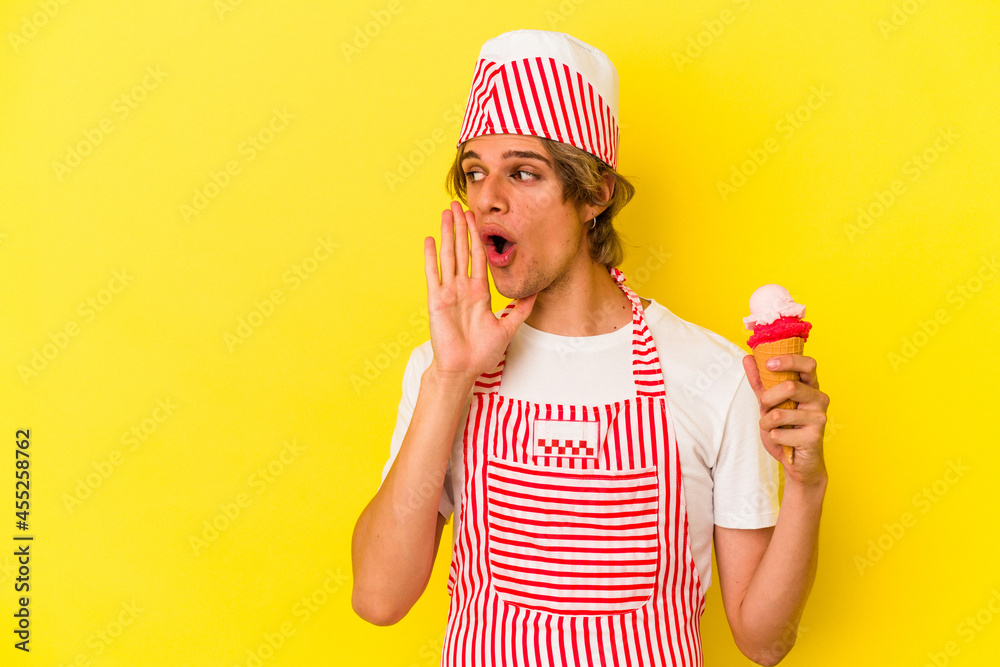 Young ice cream maker man with makeup holding ice cream isolated on yellow background is saying a secret hot braking news and looking aside Young ice cream maker man with makeup holding ice cream isolated on yellow background is saying a secret hot braking news and looking aside