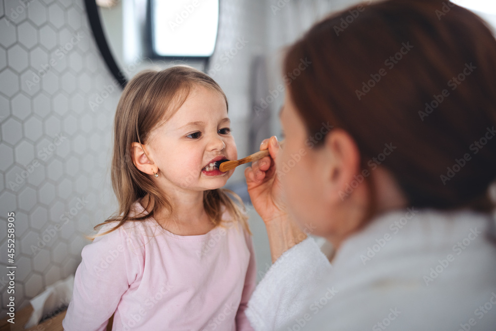Mother with small daughter brushing teeth indoors in bathroom in the evening or morning. Mother with small daughter brushing teeth indoors in bathroom in the evening or morning.
