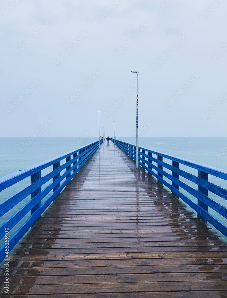 Wooden pier in the sea, gray sky background, misty rainy day