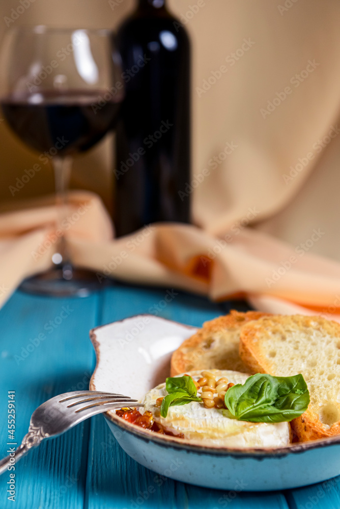 Baked camembert with sauce and toast served in a white bowl over beige cloth background. Delicious dinner idea