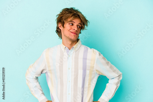 Young caucasian man with make up isolated on blue background  dreaming of achieving goals and purposes © Asier