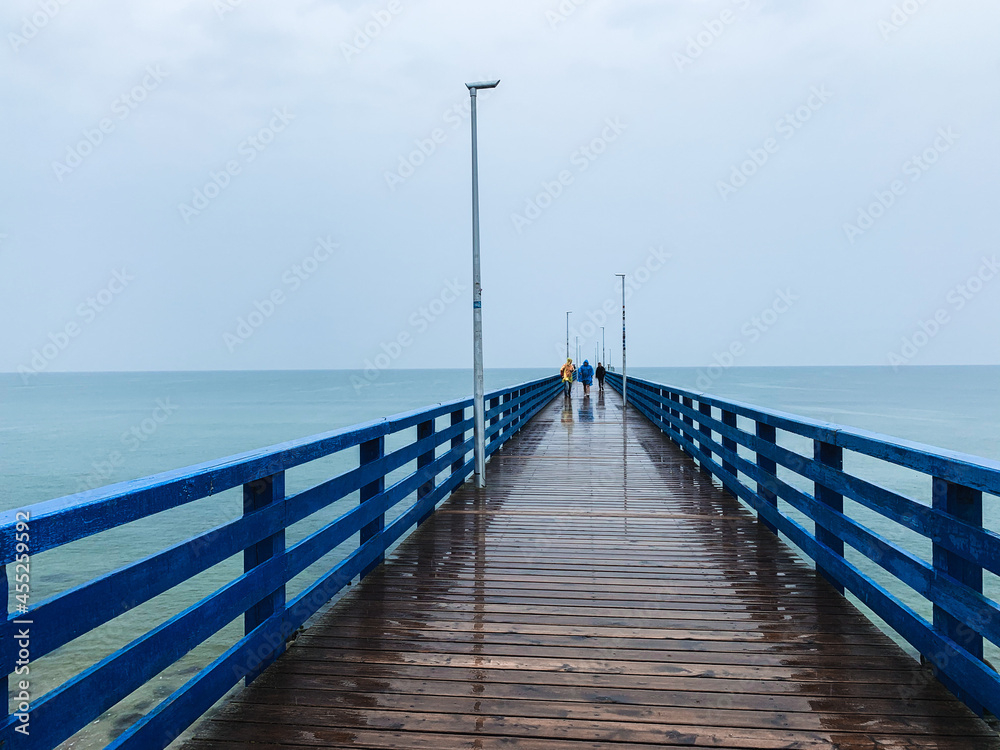 Wooden pier in the sea, gray sky background, misty rainy day