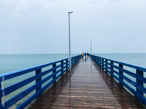 Wooden pier in the sea, gray sky background, misty rainy day © Oksana