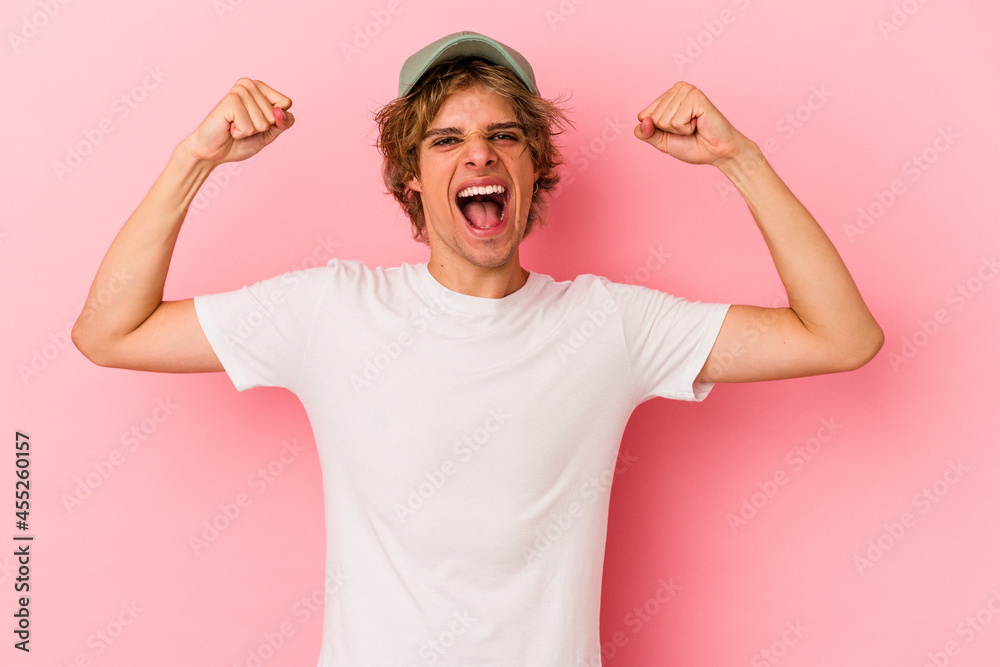 Young caucasian man with make up isolated on pink background showing strength gesture with arms, symbol of feminine power Young caucasian man with make up isolated on pink background showing strength gesture with arms, symbol of feminine power
