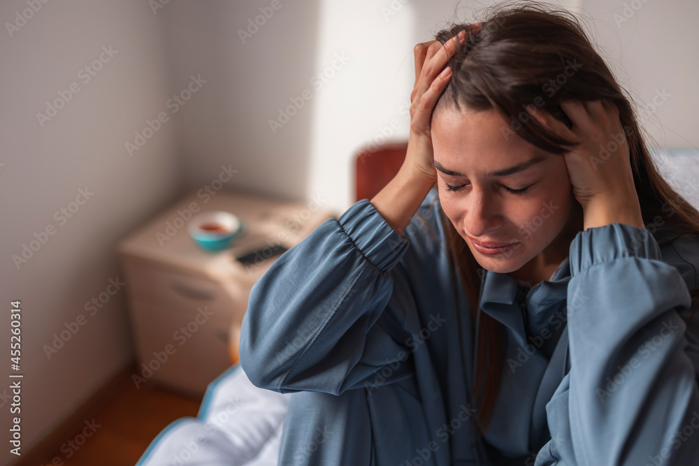 Woman holding head in hands crying in bed Woman holding head in hands crying in bed