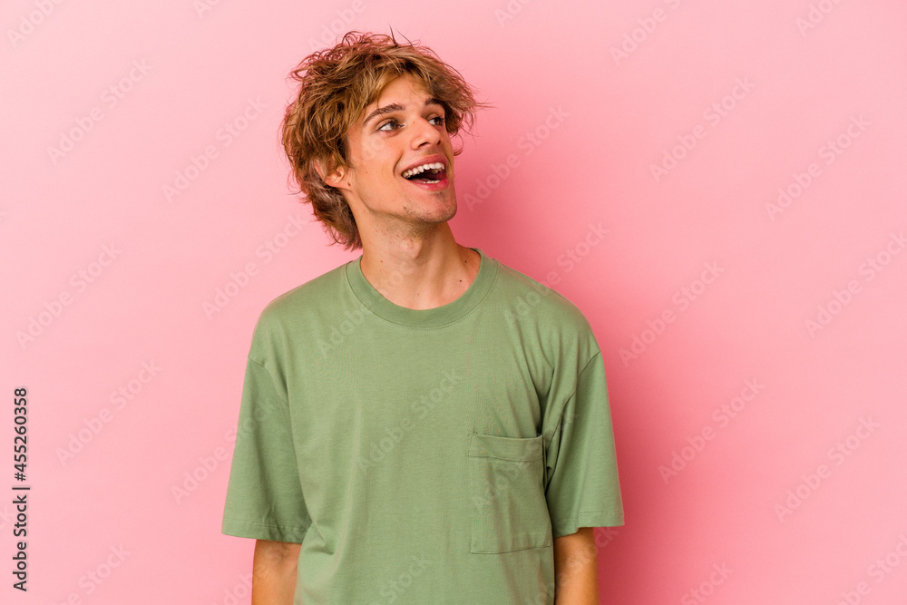 Young caucasian man with make up isolated on pink background relaxed and happy laughing, neck stretched showing teeth. Young caucasian man with make up isolated on pink background relaxed and happy laughing, neck stretched showing teeth.