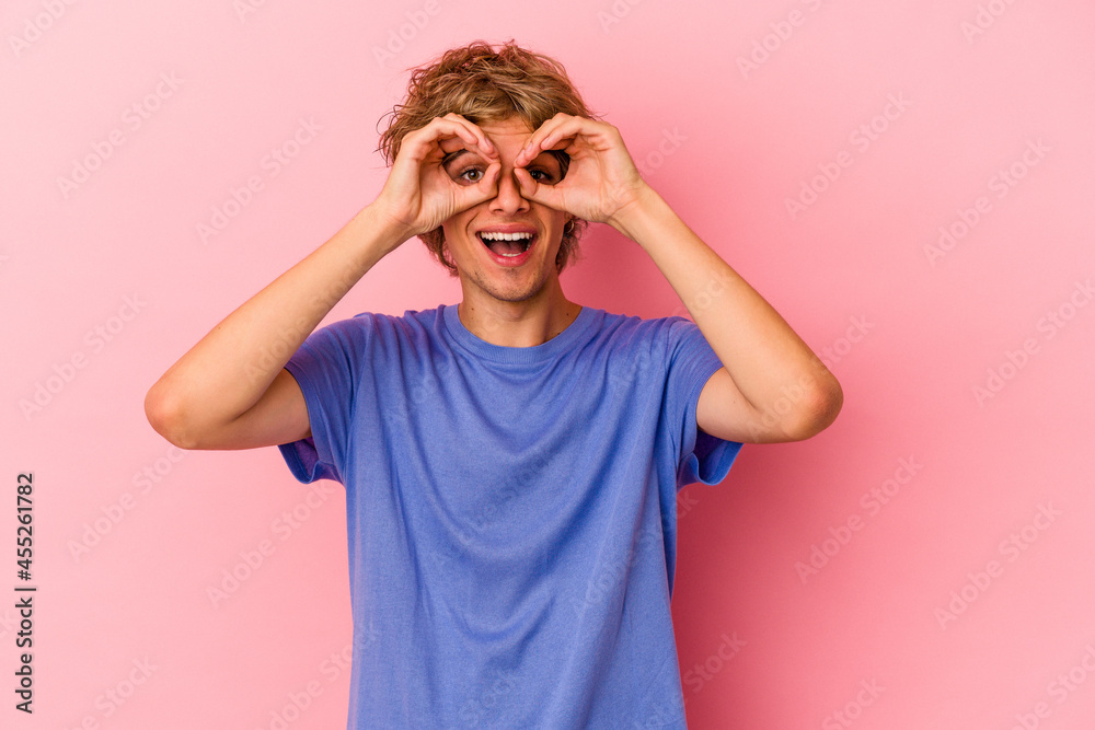 Young caucasian man with make up isolated on pink background showing okay sign over eyes Young caucasian man with make up isolated on pink background showing okay sign over eyes