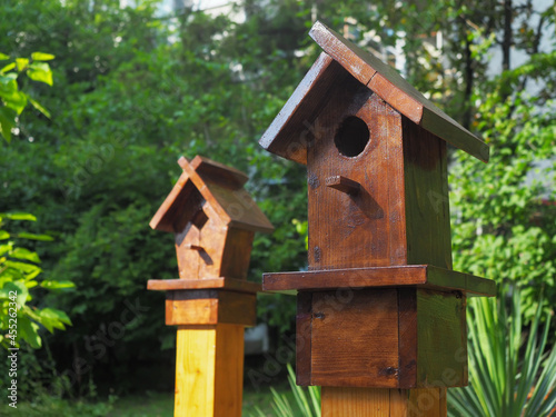 Two decorative wooden birdhouses on the background of park green plants. Closeup photo © jockermax3d