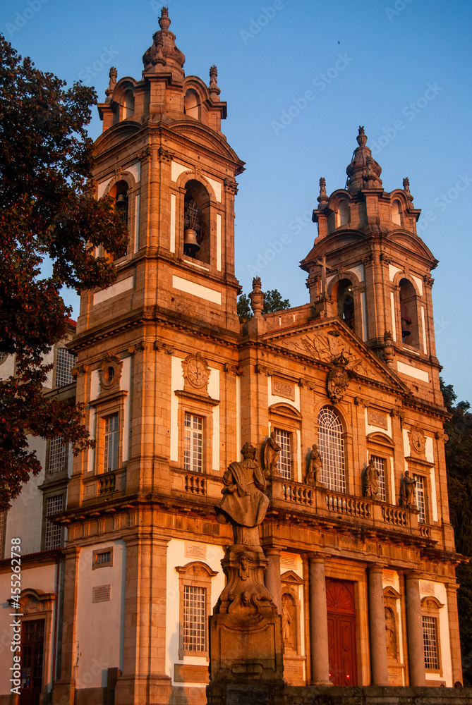 Beautiful church and a statue turn orange at sunset with beautiful clear sky - Vertcal, Bom Jesus, Braga, Portugal