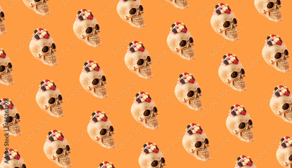Skull with candies on orange background. Creative Halloween scary concept.