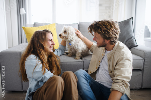 Happy young couple in love with dog indoors at home, resting.