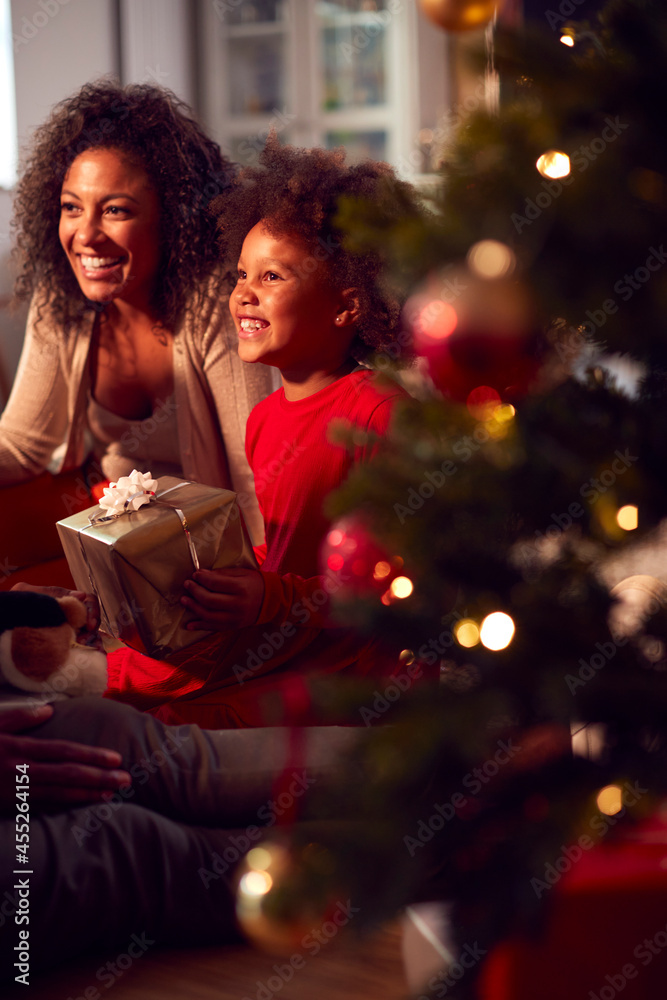 Family Exchanging And Opening Gifts Around Christmas Tree At Home