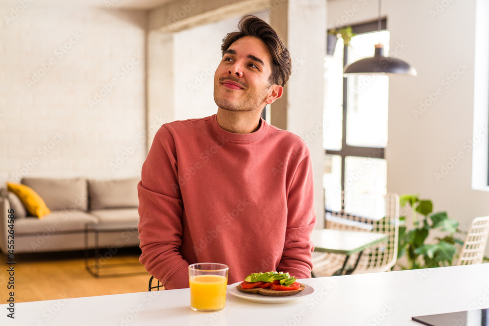 Young mixed race man having breakfast in his kitchen dreaming of achieving goals and purposes Young mixed race man having breakfast in his kitchen dreaming of achieving goals and purposes