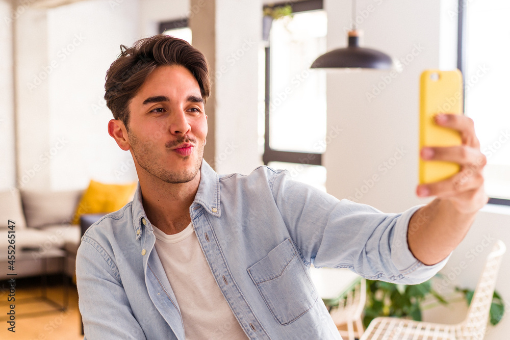 Young mixed race man talking on the phone in a kitchen Young mixed race man talking on the phone in a kitchen