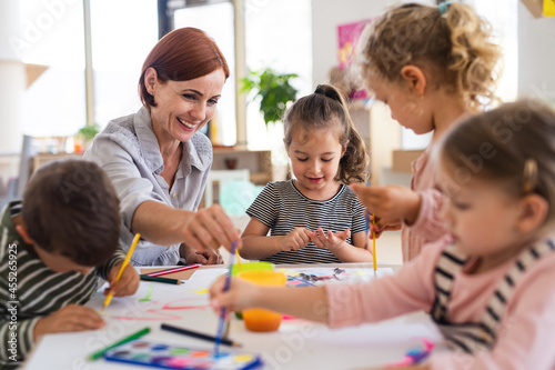 Obraz na płótnie Group of small nursery school children with teacher indoors in classroom, painting