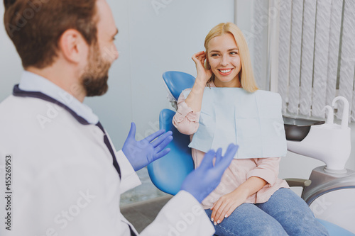 фотографія Young man dentist doctor in white gown talk speaking with patient consulting smi
