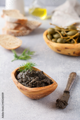 Black Tapenade or tapas, traditional Provence dish or dip with olives and basil on an old wooden table background. Selective focus. Top view