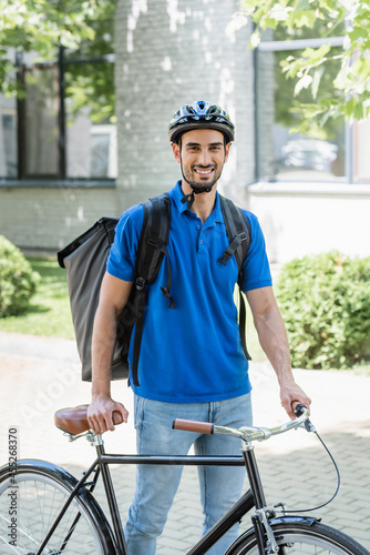 Smiling muslim deliveryman with backpack walking near bicycle outdoors © LIGHTFIELD STUDIOS