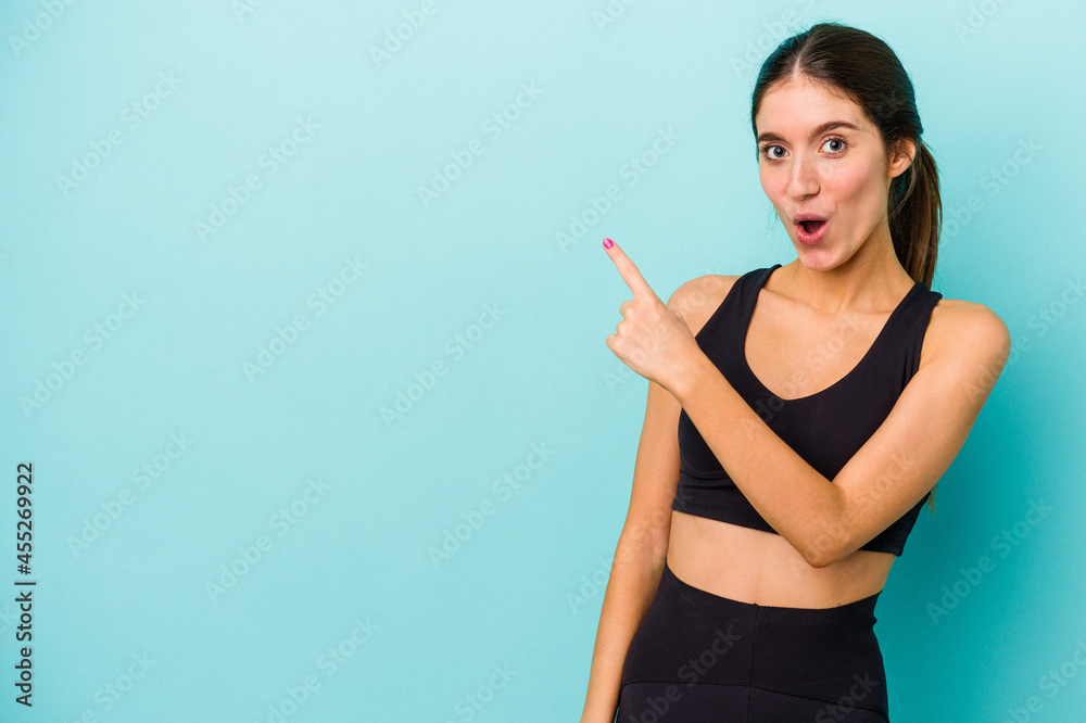 Young sporty caucasian woman isolated on blue background pointing to the side Young sporty caucasian woman isolated on blue background pointing to the side