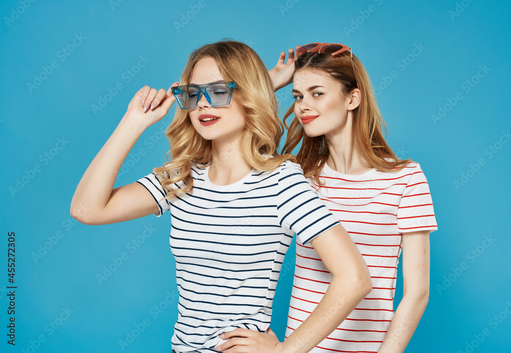 two cute girlfriends summer fashion fun hug blue background
