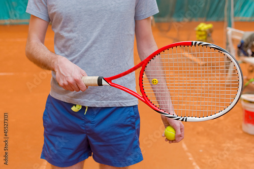Tennis player holding racket and yellow ball on the tennis court © bennian_1