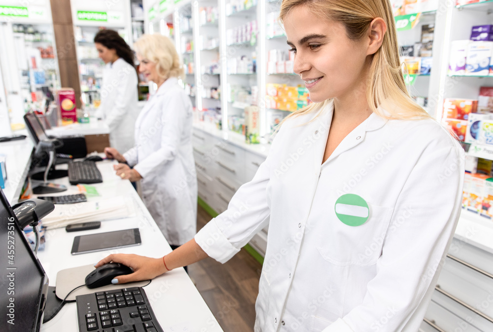 Obraz premium Young female pharmacist working at pharmacy behind the counter.