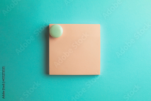 Pink sticky note paper with white circle magnet isolated over blue pastel background.,cliping path include sticky note.,Cut out stationery or memo pad.