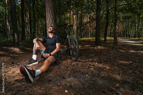 Happy bearded man relaxing after cycling in forest